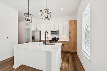 A modern kitchen with a white island and wooden cabinets.